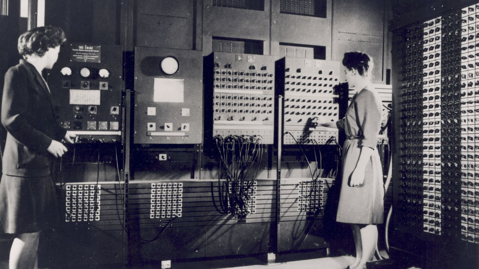 Two women setting switches on the panels of ENIAC, a room-sized early computer
